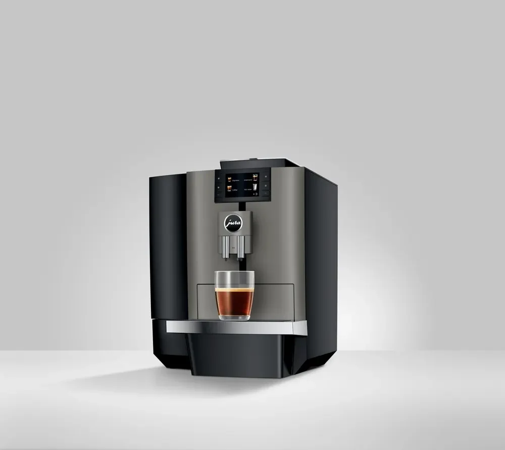 JURA X4 Dark Inox schuin van voren, met een kop koffie