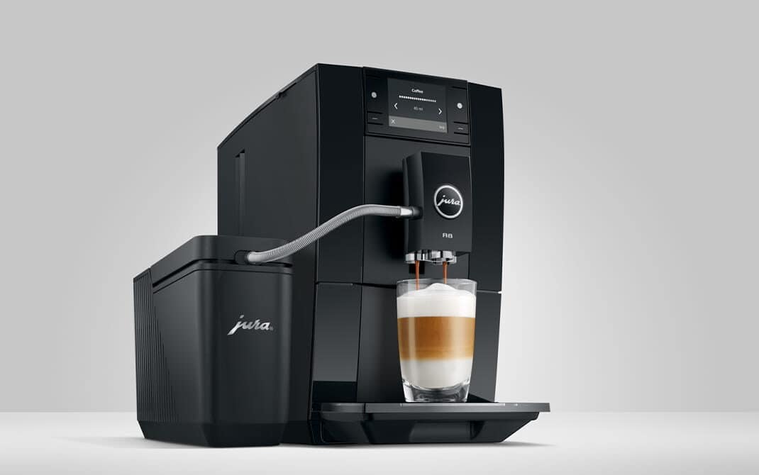 JURA A8 Piano Black zet een latte macchiato via de melkslang uit een melkhouder