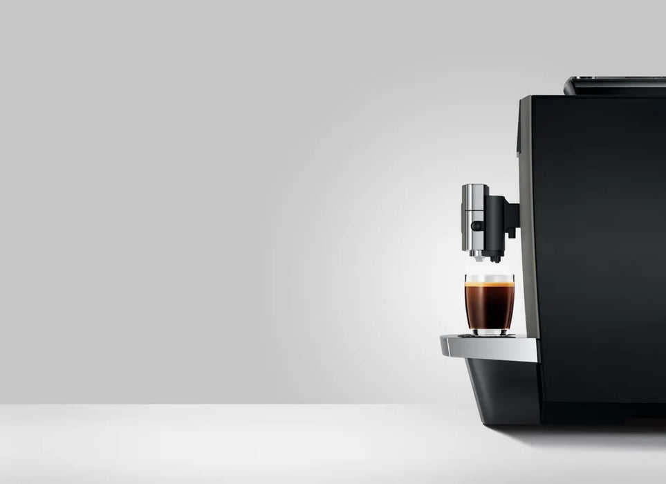 JURA X10c Dark Inox koffiemachine met kopje koffie op zilveren lekbak