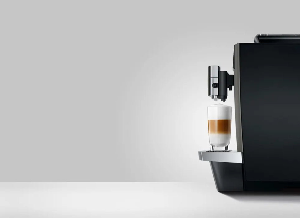 JURA X10c Dark Inox koffiemachine met glas latte macchiato op het chromen lekbakje