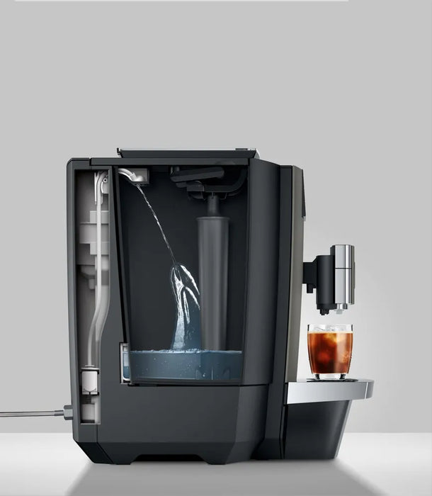 JURA X10c Dark Inox koffiemachine met waterreservoir en glas met ijskoffie op het dienblad