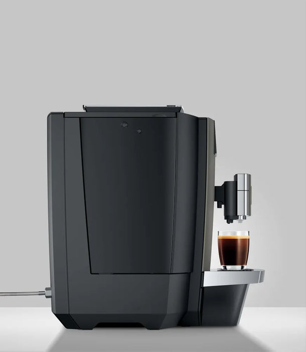JURA X10c Dark Inox koffiemachine met een kopje espresso op het chromen lekbakje