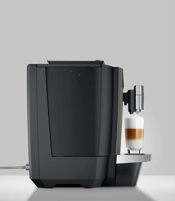 JURA X10c Dark Inox koffiemachine met glas latte macchiato op zilveren lekbak